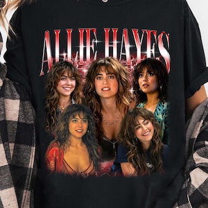 Könnte beinhalten: Ein schwarzes kurzärmeliges T-Shirt mit dem Text ALLIE HAYES in roter und weißer Schrift im oberen Bereich. Unter dem Text befinden sich fünf verschiedene fotografische Porträts derselben Person mit langem braunem Haar, die als Collage angeordnet sind.