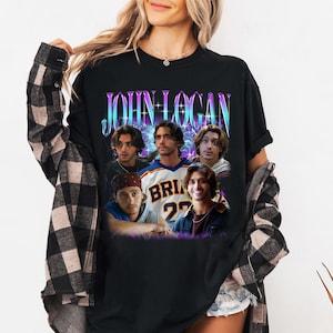 May include: A black short-sleeved t-shirt featuring a graphic print of the name JOHN LOGAN in a blue and purple gradient font. Below the text are five photographic portraits of the same person in various outfits, including a sports jersey.