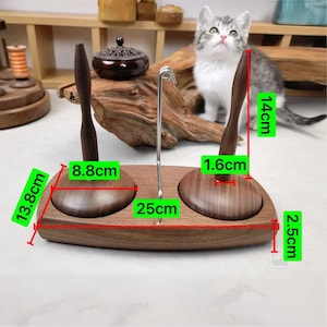 May include: A wooden incense holder with two bowls and two wooden handles. The holder is 25 cm long, 13.8 cm wide, and 2.5 cm tall. The wooden handles are 14 cm tall. A metal incense holder is in the center. A cat is in the background.