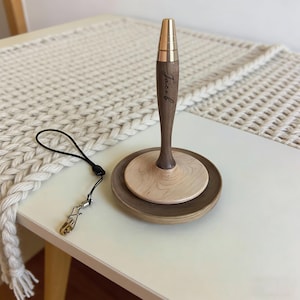 以下が含まれることがあります： 濃い茶色のベースと明るい茶色のトップが付いた木製のペンホルダー。 ペンホルダーは金色のトップで、「Jacob」という名前が側面に書かれています。 金色の留め金が付いた黒いストラップがペンホルダーに取り付けられています。