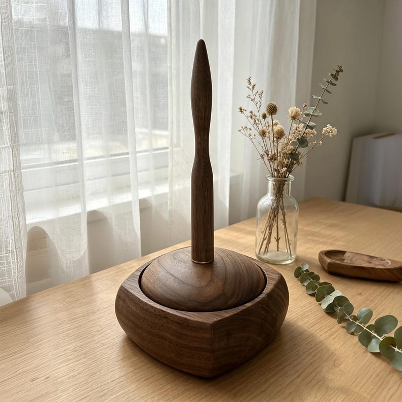 May include: A wooden paper towel holder with a dark brown finish. The holder has a square base and a tall, slender handle. The design is minimalist and elegant, suitable for a kitchen or bathroom. The holder is made of solid wood.