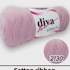 Könnte beinhalten: Eine Spule rosa Diva-Baumwollband, mit einem Gewicht von 250 Gramm und 150 Metern. Das Etikett enthält die Aufschrift "Oeko-tex" und "Global Recycled Standard". Der Farbcode ist 2130.