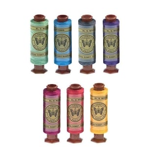 Peut inclure: Huit bobines de fil à broder colorées. Chaque bobine a une base et un dessus marron. Les couleurs des fils comprennent le vert, le bleu, le gris, le violet, le rose, le rouge et le jaune. Les bobines ont des étiquettes avec du texte et un motif de papillon.