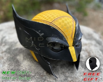 Op de afbeelding: Een zwart-gele helm met een gestructureerd dambordpatroon op de bovenkant en hoge, puntige oordoppen. Het oppervlak vertoont subtiele krasjes. De tekst op de afbeelding luidt MIDGARD BLACKSMITH, NEW COMFY+ Interior Design en FREE GIFT.