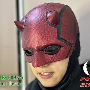 May include: A red textured superhero mask with black accents and two horns. The mask has eye openings and is worn over a black balaclava. Text on the image reads "NEW COMFY+ Interior Design" and "FREE GIFT".
