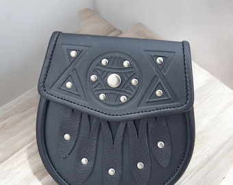 May include: Black leather sporran with a flap featuring a geometric design and silver studs. The sporran has a rounded bottom with decorative leather fringe and silver studs. A traditional accessory.
