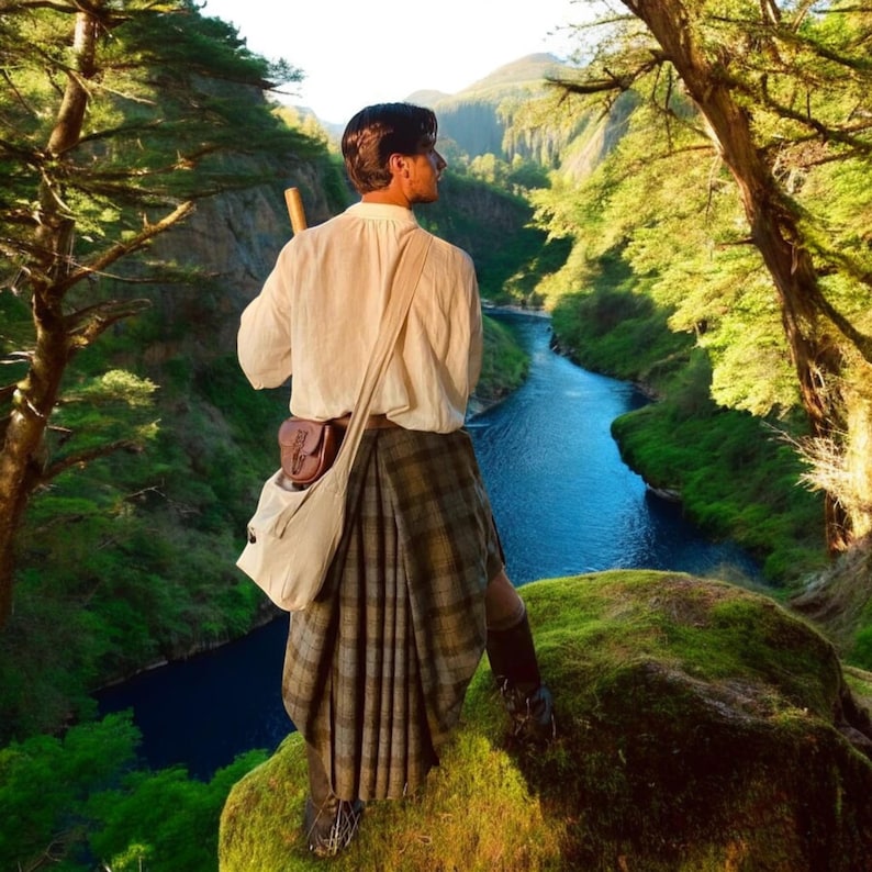 May include: A white long-sleeved shirt, a pleated tartan kilt in shades of brown and grey, a brown leather pouch, and a cream-coloured canvas shoulder bag. The outfit includes dark boots and a wooden staff, worn by a person standing on a mossy cliff.