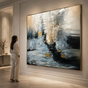Puede incluir: Gran pintura abstracta con marco dorado. La obra presenta una superficie texturizada con tonos azules, negros y dorados. La pintura se exhibe en una pared blanca en una habitación bien iluminada.