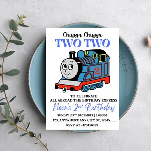 Könnte beinhalten: Eine Geburtstagseinladung mit einer blauen Cartoon-Zug-Illustration und dem Text "Chugga Chugga TWO TWO". Die Einladung lautet "Neon's 2nd Birthday" und enthält Veranstaltungsdetails. Die Einladung liegt auf einem blauen Teller.