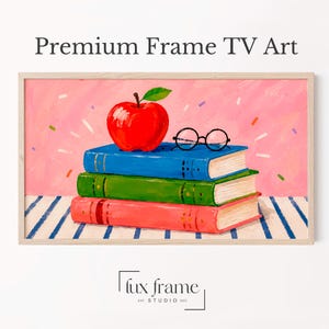 May include: A digital artwork titled Premium Frame TV Art featuring a stack of three books in blue, green, and red, topped with a bright red apple and black-rimmed glasses. The background is pink with colourful confetti, set on a blue striped surface.