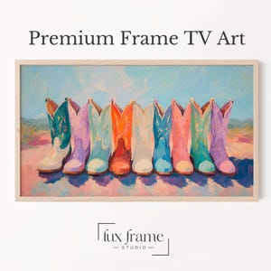 以下が含まれることがあります： Premium Frame TV Artと題された長方形のデジタルアートプリント。ティール、ラベンダー、ライトブルー、オレンジ、ホワイト、ピンクの色合いの9足のカラフルなカウボーイブーツが、柔らかな青い空と質感のある地面を背景に一列に並んでいる様子が描かれています。