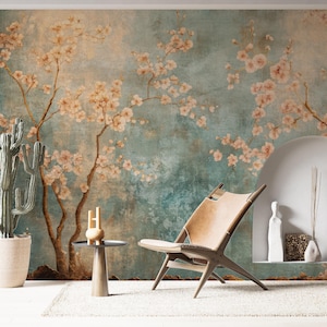 May include: A serene interior scene featuring a teal and beige floral mural as a backdrop. A wooden chair with a tan leather seat sits on a white rug. A potted cactus and a small side table with decor complete the space.