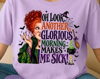 May include: A light purple t-shirt featuring a graphic of a woman with voluminous red hair in a green dress. The text reads, "OH LOOK, ANOTHER GLORIOUS MORNING... MAKES ME SICK!" alongside illustrations of a witch hat, spiderweb, broom, cauldron, and bats.