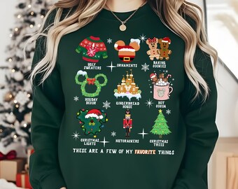 May include: A dark green long-sleeve sweatshirt featuring a graphic print of nine Christmas-themed icons including a sweater, ornaments, cookies, wreath, castle, cocoa, lights, nutcracker, and tree, with the text THESE ARE A FEW OF MY FAVORITE THINGS.