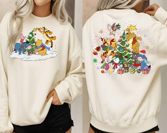 May include: Cream-colored sweatshirt featuring a colorful Christmas-themed graphic of Winnie the Pooh and friends decorating a Christmas tree. The front and back of the sweatshirt are shown. The characters include Pooh, Piglet, Tigger, Eeyore, and Owl.