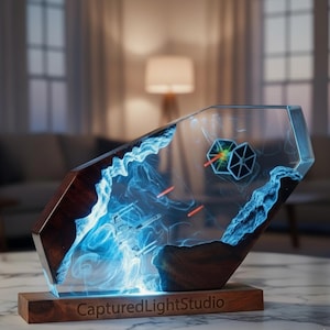 May include: A unique, handcrafted resin art piece featuring a Star Wars theme. The artwork showcases a battle scene with TIE fighters and laser fire, encased in clear resin with blue lighting effects. The base is made of dark wood, with "CapturedLightStudio" engraved.