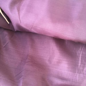 Puede incluir: Primer plano de una tela morada con un brillo sutil. La tela parece ser un material de forro, con costuras visibles en los bordes. El color es un morado profundo y apagado, con ligeras variaciones de tono.