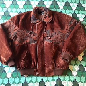Pode incluir: Um blusão bomber de camurça castanha com um painel de tecido estampado no peito e nas mangas, gola dobrada, fecho de correr frontal com carcela de botões e punhos e bainha em malha canelada para um ajuste estruturado.