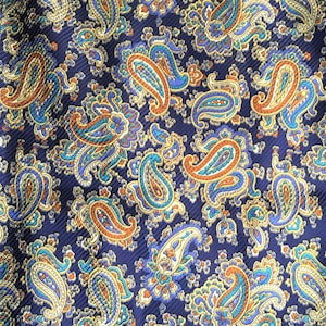 May include: A navy blue fabric with a paisley pattern in shades of gold, orange, and teal.