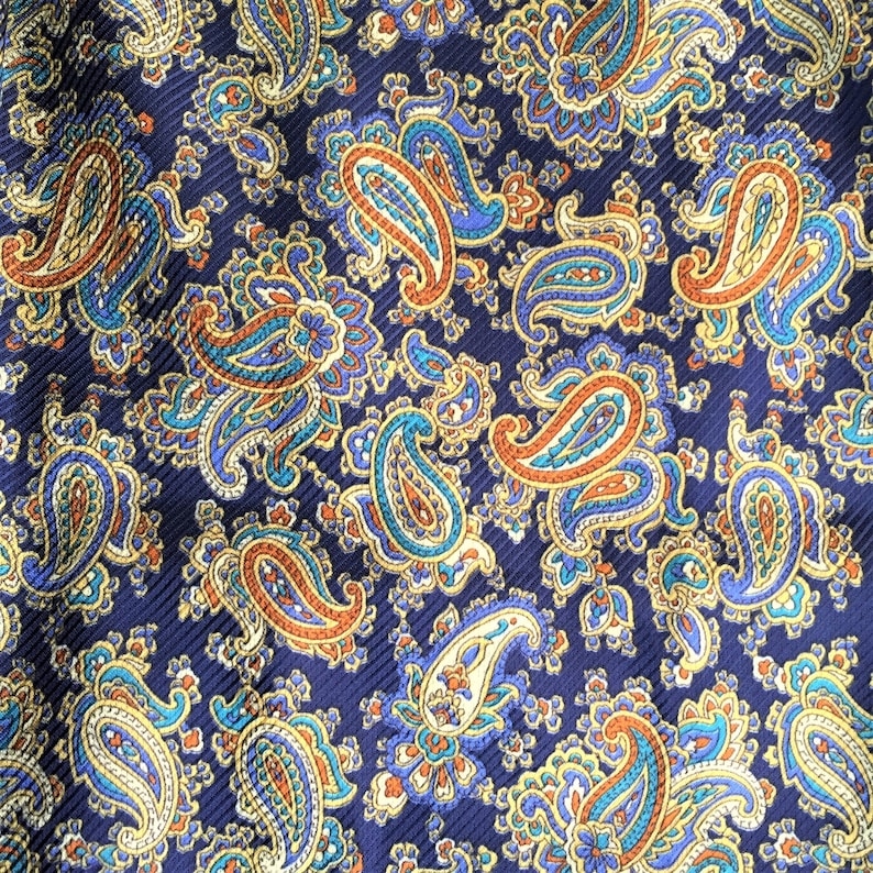 May include: A navy blue fabric with a paisley pattern in shades of gold, orange, and teal.