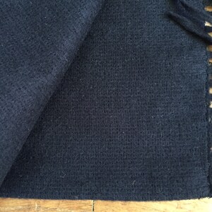 May include: A dark blue, soft, woven scarf with a fringe edge.