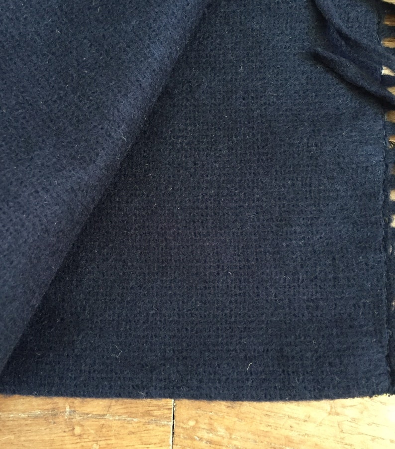 May include: A dark blue, soft, woven scarf with a fringe edge.
