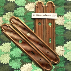 Puede incluir: Tres placas de puerta de metal dorado antiguo con un diseño acanalado decorativo y bordes redondeados. Las placas tienen un pequeño agujero en el centro y están etiquetadas como "LA DOUCHKA VINTAGE".