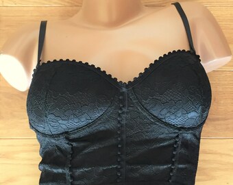May include: Black lace bustier top with adjustable straps and a sweetheart neckline. The top has a boned bodice and is decorated with small black beads.