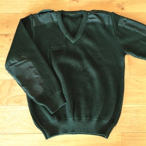 May include: A dark green knitted sweater with a v-neck and reinforced elbow patches.