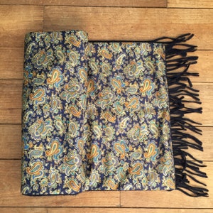 May include: A blue paisley patterned scarf with fringe on the ends.