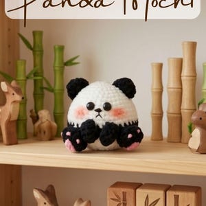 May include: A crocheted panda mochi plushie with black and white yarn, black paws, and pink cheeks. The panda is sitting on a wooden shelf with other wooden figurines and bamboo stalks. The text "Panda Mochi" is at the top.