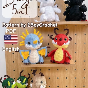 Könnte beinhalten: Eine Sammlung gehäkelter Drachenfiguren in verschiedenen Farben, darunter Weiß, Schwarz, Blau, Rot, Grün und Beige. Die Drachen sind auf Holzregalen ausgestellt. Das Bild enthält den Text "Dragon 5 in 1" und "Pattern by 2BoyCrochet PDF English".