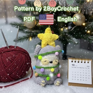 May include: A grey crocheted sloth Christmas decoration with a yellow star, wrapped in string lights. A ball of red yarn and crochet hooks are in the background. The text reads "Pattern by 2BoyCrochet PDF English". A calendar shows the date October 10, 2023.