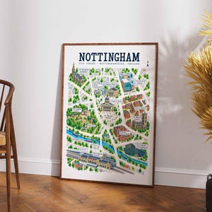 May include: A framed map print titled NOTTINGHAM CITY CENTRE NOTTINGHAMSHIRE, ENGLAND. The illustration features a colourful, detailed bird's-eye view of the city, highlighting landmarks like Nottingham Castle, Old Market Square, and the canal.