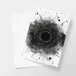 May include: A white greeting card with a black hole design. The artwork features a central black circle surrounded by a textured, splattered effect in shades of grey and black, with small white speckles.