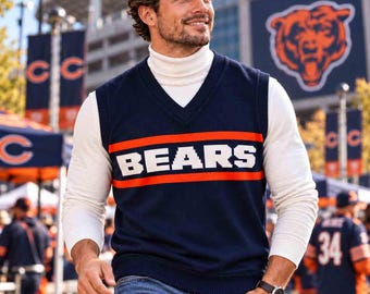 May include: A navy blue V-neck sweater vest featuring the word BEARS in white block letters centered between two horizontal orange stripes, worn over a white long-sleeve turtleneck shirt and paired with blue denim jeans.