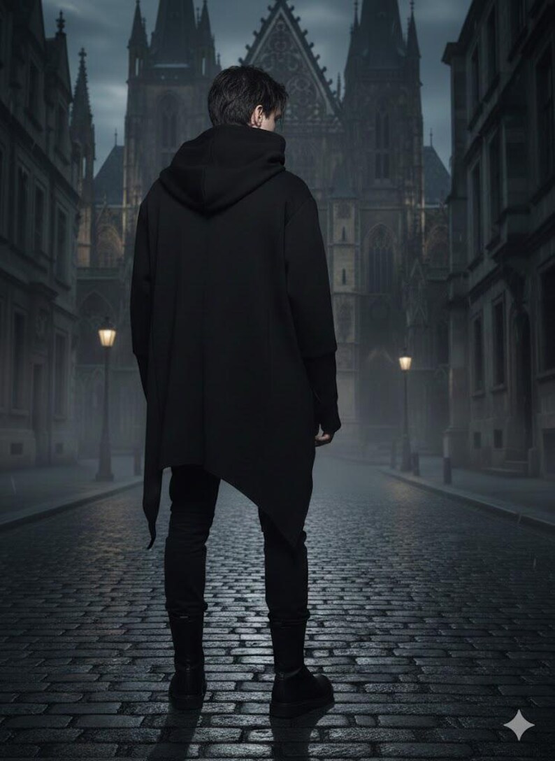 K&ouml;nnte beinhalten: Eine Person in einem schwarzen Kapuzenmantel mit asymmetrischem Saum, schwarzer Hose und Stiefeln steht auf einer Kopfsteinpflasterstra&szlig;e. Im Hintergrund befinden sich ein Geb&auml;ude im gotischen Stil und Stra&szlig;enlaternen, was eine dunkle, atmosph&auml;rische Szene erzeugt.