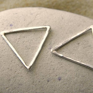 Op de afbeelding: Twee zilveren driehoekige oorringen met een gehamerde textuur.