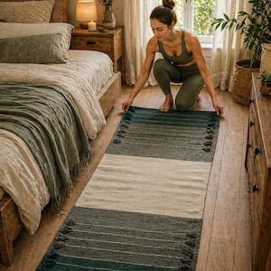 Puede incluir: Una alfombra rectangular en tonos turquesa, gris y crema, con un dise&ntilde;o a rayas y borlas en los extremos. La alfombra est&aacute; colocada sobre un suelo de madera. Las dimensiones de la alfombra no son visibles.