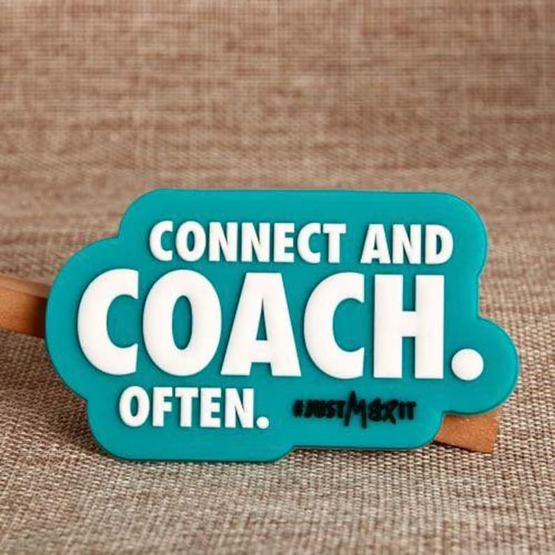 May include: A teal-colored rectangular magnet with rounded edges. The magnet features the white text "CONNECT AND COACH OFTEN." and the hashtag "#JUSTMERIT" in black. The magnet is on a textured brown surface.