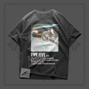 Puede incluir: Camiseta gris oscuro con el texto "FIVE FIVE 2018" y una foto de una persona cerca de un coche. Debajo del texto hay títulos de canciones. Tiene cuello redondo y mangas cortas.