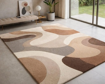 Può includere: Un tappeto rettangolare caratterizzato da un motivo astratto su larga scala con forme organiche fluide in una palette di crema, beige, marrone chiaro e marrone scuro. Il tappeto presenta una superficie trapuntata con linee curve e morbide.
