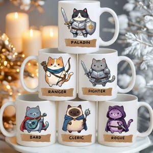 May include: White ceramic mugs featuring cartoon cats in fantasy roles: Paladin, Ranger, Fighter, Bard, Cleric, and Rogue. Each cat is depicted with appropriate attire and accessories, such as swords, bows, and capes. The mugs have a standard handle and are suitable for hot beverages.