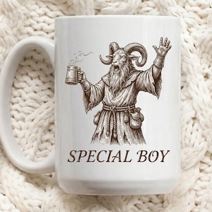 May include: White ceramic mug featuring a detailed illustration of a goat-like figure in robes, holding a mug of steaming liquid and raising a hand. The text "SPECIAL BOY" is printed in brown below the illustration. The mug has a large handle.