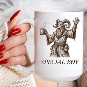 May include: White ceramic mug featuring a detailed illustration of a goat-like figure in robes, holding a mug of ale and raising a hand. The text "SPECIAL BOY" is printed below the illustration. The mug has a large handle.