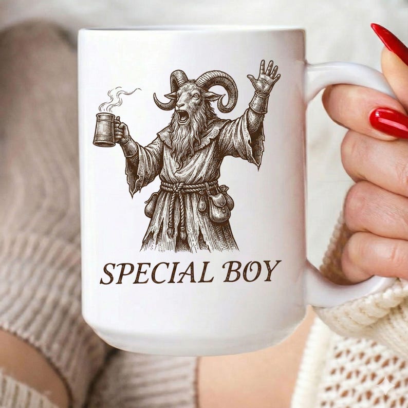 May include: White ceramic mug with a black illustration of a goat-like figure holding a mug and raising a hand. The text "SPECIAL BOY" is printed below the illustration. The mug has a large handle.