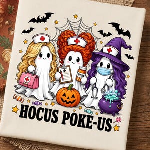 May include: A white t-shirt featuring a graphic of three ghost nurses with blonde, red, and purple hair, wearing nurse caps with red crosses. They hold a medical bag, clipboard, and medicine bottle. Below is a pumpkin and the text HOCUS POKE-US.
