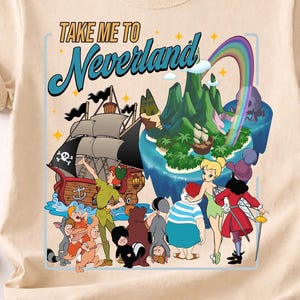 Może przedstawiać: Beżowa koszulka z kolorową grafiką z Nibylandii. Projekt zawiera statek piracki, postacie, tęczę i napis "TAKE ME TO Neverland". Koszulka ma krótkie rękawy i okrągły dekolt.