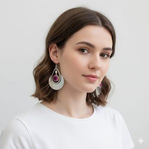 Puede incluir: Pendientes plateados con forma de lágrima y una gema magenta en el centro, con un pequeño acento de perla. Los pendientes tienen un diseño en capas y un acabado pulido. Un accesorio elegante.