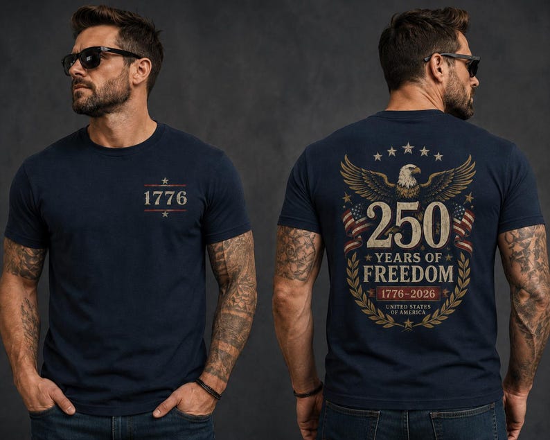 May include: A navy blue short-sleeve t-shirt featuring the text 1776 on the front chest. The back displays a graphic of a bald eagle, American flags, and the text 250 YEARS OF FREEDOM 1776-2026 UNITED STATES OF AMERICA in gold and white.